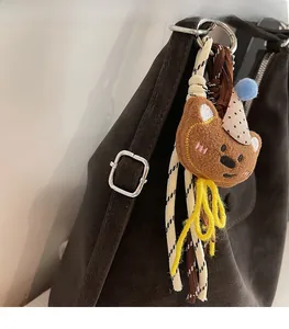 Detail van een schattige bruine pluche beer met feesthoedje aan een leren schoudertas
