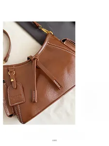 Dettaglio della borsa a secchiello in pelle marrone vintage con cuciture bianche a contrasto