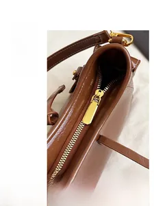 Dettaglio della cerniera dorata su borsa a secchiello in pelle marrone pregiata