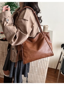 Primer plano de un bolso tote grande marrón con lazos laterales y textura de cuero fino