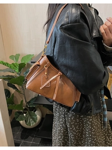 Dettaglio della borsa a secchiello vintage in pelle marrone con cuciture bianche a vista
