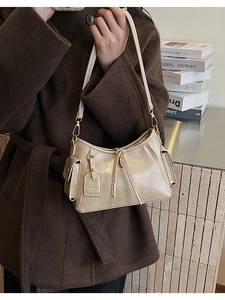 Dettaglio borsa a mezzaluna beige con etichetta FASHION BAGS e finiture dorate