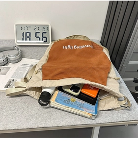 Dettaglio della borsa capiente che mostra spazio per tablet, riviste e borracce d'acqua