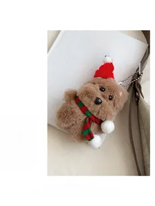 Detailed view of a brown plush teddy bear keychain with a festive red hat and striped scarf