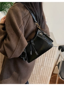 Dettaglio della borsa a spalla nera lucida con cuciture bianche a contrasto e nappa decorativa