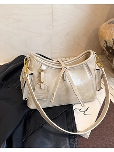 Dettaglio della borsa beige in ecopelle con finiture dorate e targhetta su pelle nera