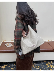 Detail view of large cream tote bag featuring dark brown trim and leather brand tag