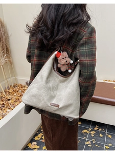 Detail of vintage beige bucket bag with brown trim and festive teddy bear plush charm