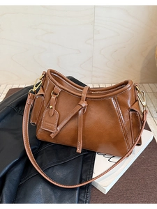 Dettaglio borsa in pelle marrone con cuciture a contrasto e hardware dorato