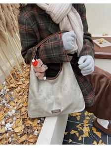 Detail of grey vintage tote bag with deep brown leather trim and cute teddy bear charm
