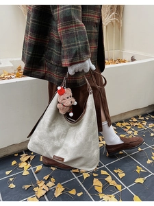 Detail of soft canvas tote bag with brown leather strap and cute teddy bear pendant