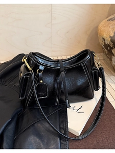 Dettaglio della borsa nera in pelle lucida con cuciture a contrasto e fibbie dorate fini