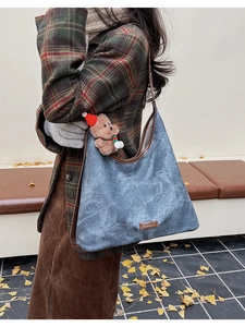 Close-up of blue vintage crossbody bag with brown trim and cute teddy bear charm