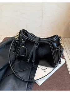 Dettaglio borsa a spalla nera lucida con cuciture a contrasto bianche e hardware dorato