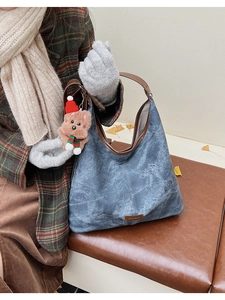 Detail of vintage blue bucket bag with brown leather trim and cute teddy bear charm