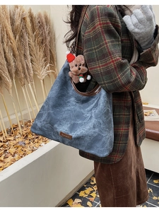 Detail of blue retro tote bag with leather logo patch and cute teddy bear charm