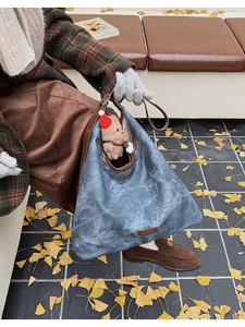 Close-up of retro washed blue bucket bag with brown leather trim and bear plush charm