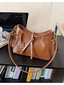 Dettaglio borsa a secchiello vintage marrone con cuciture bianche e finiture dorate