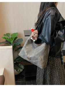 Grey hobo bag in matte leather featuring a brown plush bear charm with Christmas accessories