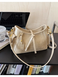 Dettaglio della borsa in pelle PU beige con finiture dorate e decorazione con corda annodata