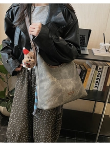 Detail view of large grey tote bag with marble texture and cute teddy bear charm
