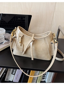 Dettaglio borsa a secchiello beige in ecopelle con tasche e finiture metalliche oro