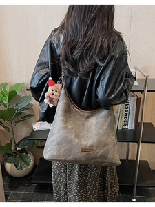 Detail of grey Hobo bag with brown leather strap and festive bear pendant accessory