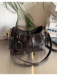 Dettaglio borsa a spalla in pelle lucida marrone scuro con cuciture e finiture dorate