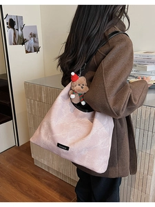 Detail of light pink marble pattern tote bag with teddy bear pendant on shoulder
