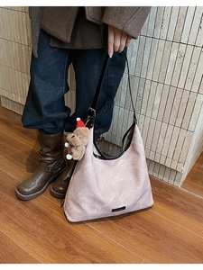 Close-up of pink bucket bag with cloud texture, black handle, and plush bear charm