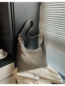 Detail of grey hobo bag with Fashion&Bags text and a vintage knot metal charm