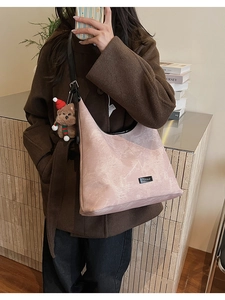 Detail of light pink textured hobo bag with adjustable strap and cute teddy bear charm