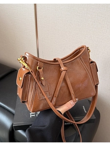 Dettaglio della borsa vintage in pelle marrone con cuciture bianche e ciondolo moda