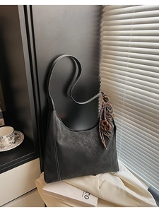 Detailed macro view of black faux leather shoulder bag with contrast white stitching