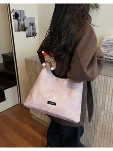 Detail of pink marble pattern tote bag with teddy bear charm on model in brown coat