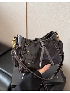 Dettaglio borsa in pelle marrone scuro cerata con cuciture a contrasto e ganci dorati