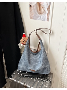 Detail of blue-grey washed canvas Hobo bag with leather trim and brown teddy bear charm
