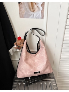 Detail of a pink textured hobo bag featuring black trim and a cute teddy bear charm