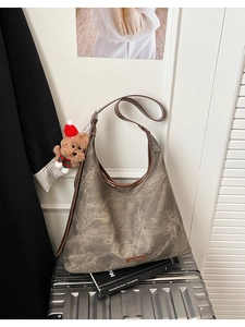Detail view of large bucket bag with leather straps and a cute puppy plush charm