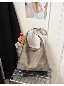 Detail of taupe vintage large bucket bag with mottled texture and plush bear charm