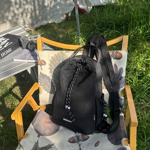 Dettaglio dello zaino in nylon nero con coulisse e logo APASTICA su sedia in tela