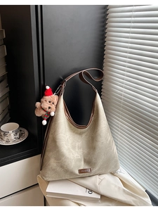 Detail of taupe hobo bag with dark brown trim and a cute plush bear charm accessory