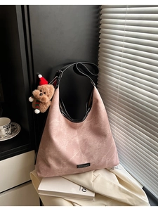 Pink matte hobo bag detail with black trim and a cute teddy bear plush charm