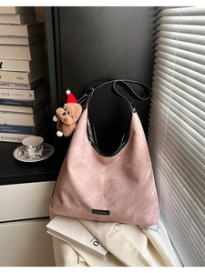 Close-up of pink retro leather hobo bag with wide black strap and cute plush bear charm