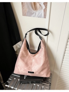 Close-up of pink large Hobo shoulder bag with black trim on a metallic suitcase