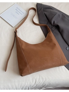 Detailed view of brown moon bag with white contrast stitching and adjustable strap