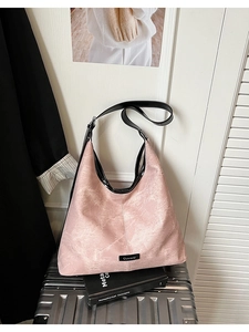 Detailed texture of pink vintage bucket bag placed on a silver metallic suitcase