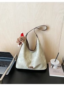 Detail of grey-green tote bag with vintage PU leather texture and cute bear charm