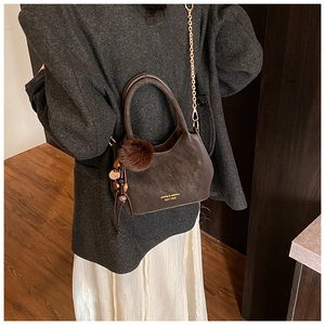 Vue détaillée du sac seau marron vintage avec chaîne dorée et breloque pompon