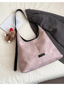 Close-up of pink moiré leather bucket bag with cute bear charm and black shoulder strap